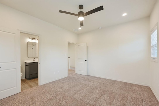 unfurnished bedroom featuring ensuite bath, ceiling fan, sink, and light colored carpet