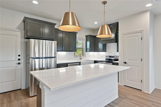 kitchen featuring appliances with stainless steel finishes, decorative light fixtures, a kitchen island, and light stone counters