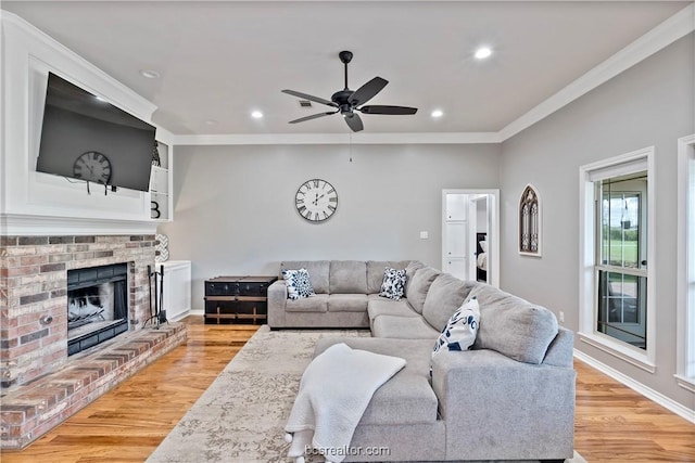 living room featuring light hardwood / wood-style floors, a brick fireplace, ceiling fan, and ornamental molding