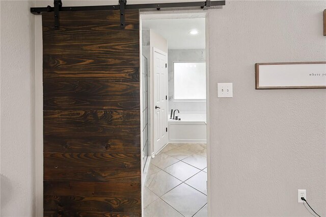 corridor featuring light tile patterned flooring and a barn door