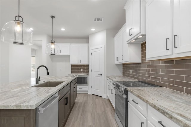 kitchen featuring white cabinetry, appliances with stainless steel finishes, decorative light fixtures, and sink