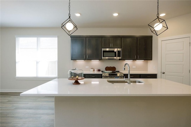 kitchen featuring light countertops, pendant lighting, stainless steel microwave, and a sink