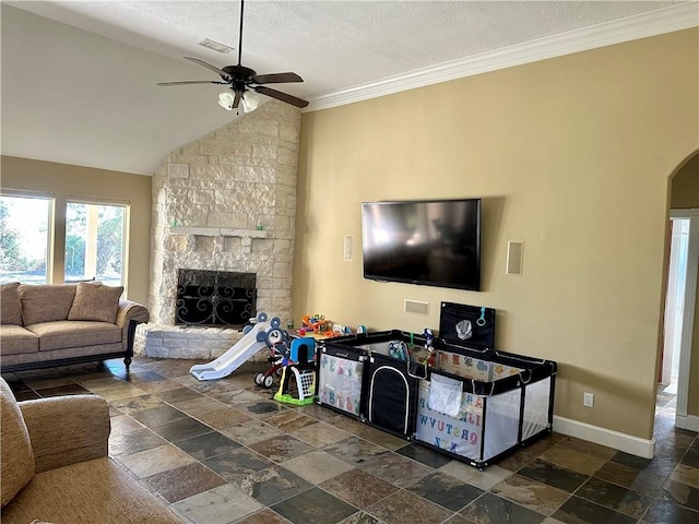 living room with ornamental molding, a textured ceiling, vaulted ceiling, ceiling fan, and a stone fireplace