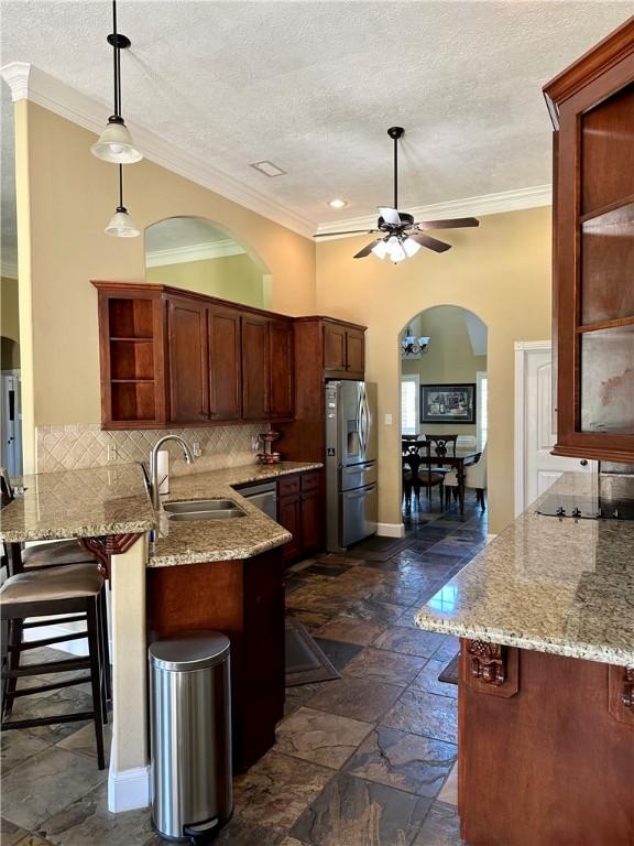 kitchen with hanging light fixtures, sink, appliances with stainless steel finishes, kitchen peninsula, and a breakfast bar area