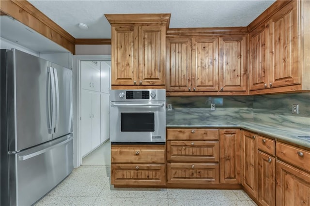 714 S Rosemary Dr, Bryan, TX 77802 - kitchen with appliances with stainless steel finishes, dark speckled floor, backsplash, and brown cabinets