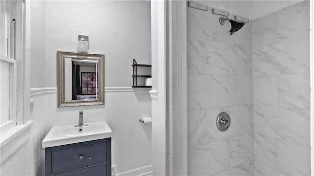 full bathroom with a shower, vanity, and wainscoting