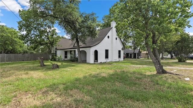 view of side of property featuring stucco siding, a shingled roof, and a chimney