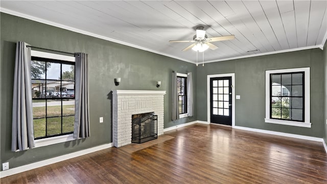unfurnished living room with ceiling fan, crown molding, wood finished floors, a brick fireplace, and baseboards