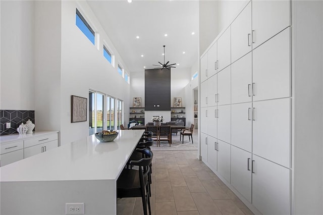 kitchen with a towering ceiling, white cabinetry, a kitchen breakfast bar, and a center island