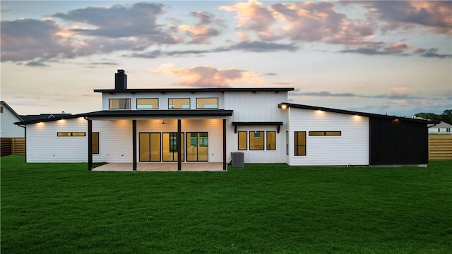 back house at dusk featuring a patio and a yard