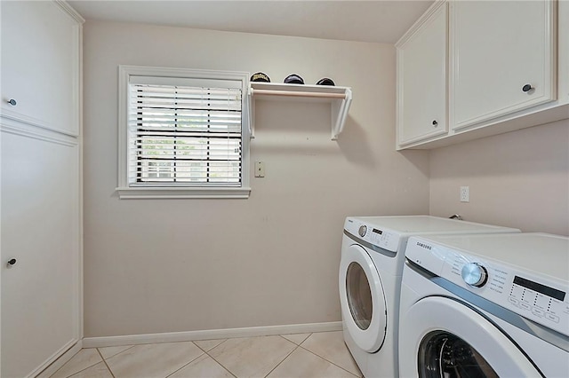 laundry room featuring light tile patterned flooring, washer and dryer, and cabinets