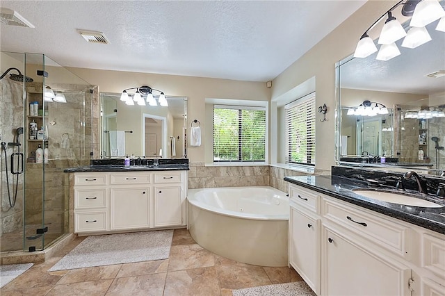 bathroom with a textured ceiling, tile patterned floors, separate shower and tub, and vanity