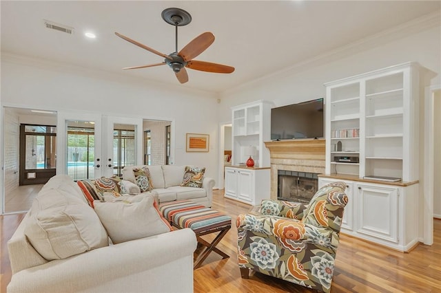 living room with ceiling fan, french doors, a fireplace, and ornamental molding