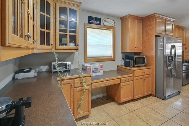 kitchen featuring built in desk, light tile patterned floors, and appliances with stainless steel finishes