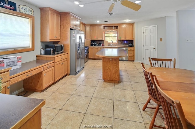 kitchen with sink, ceiling fan, light tile patterned floors, appliances with stainless steel finishes, and a kitchen island