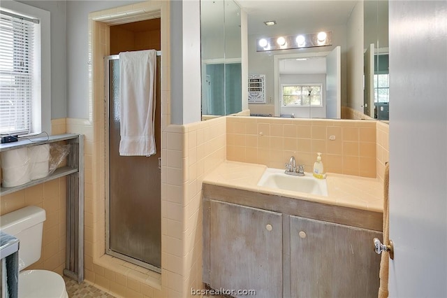 bathroom with an enclosed shower, vanity, toilet, and tile walls