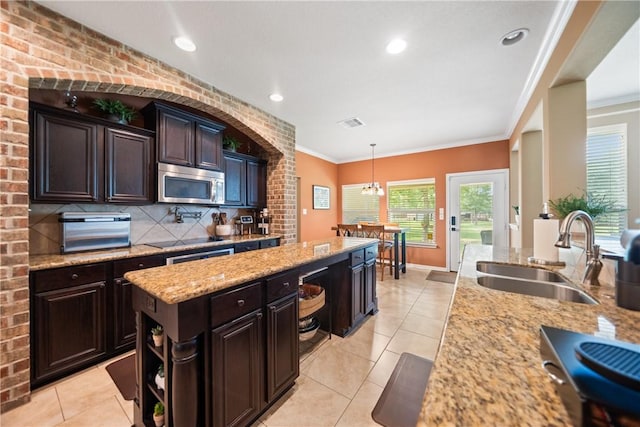 32041 Fm 1736th Rd, Hempstead, TX 77445 - kitchen with stainless steel microwave, a sink, a kitchen island, light stone countertops, and light tile patterned floors