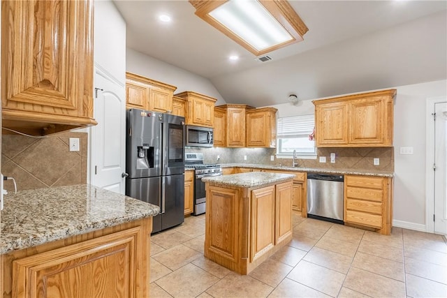 kitchen with light stone counters, light tile patterned floors, a center island, and appliances with stainless steel finishes