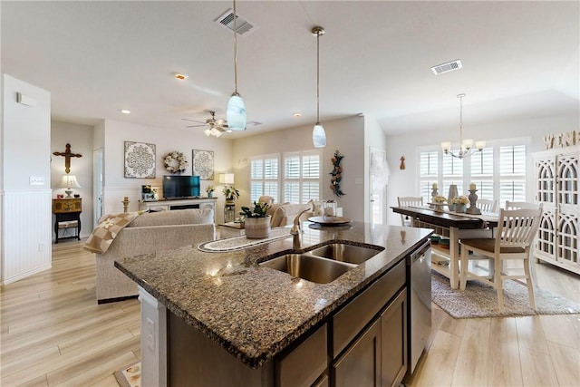 kitchen with ceiling fan with notable chandelier, dark stone countertops, sink, stainless steel dishwasher, and dark brown cabinets