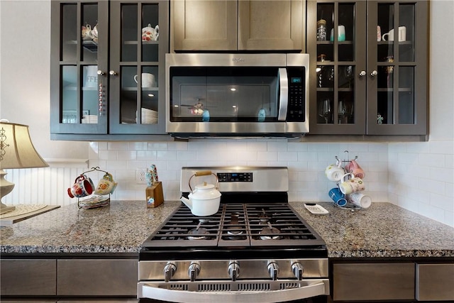 kitchen featuring decorative backsplash, dark stone countertops, and stainless steel appliances