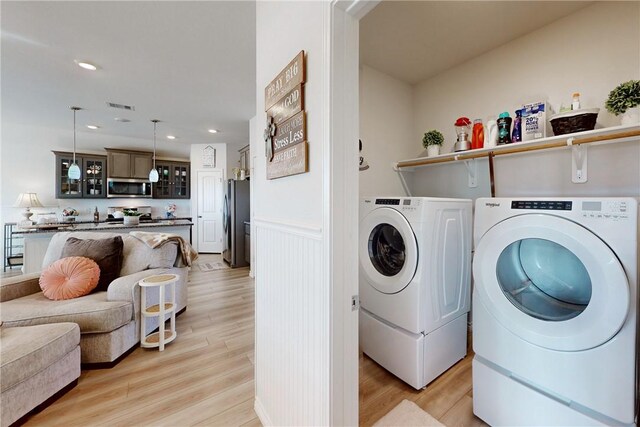 laundry room with independent washer and dryer and light wood-type flooring