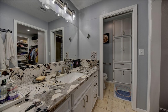 1600 Pecan St, Brenham, TX 77833 - bathroom featuring vanity, a walk in closet, toilet, tile patterned flooring, and baseboards
