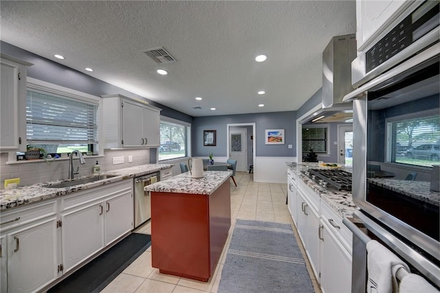 1600 Pecan St, Brenham, TX 77833 - kitchen with appliances with stainless steel finishes, a sink, a kitchen island, light tile patterned floors, and a textured ceiling