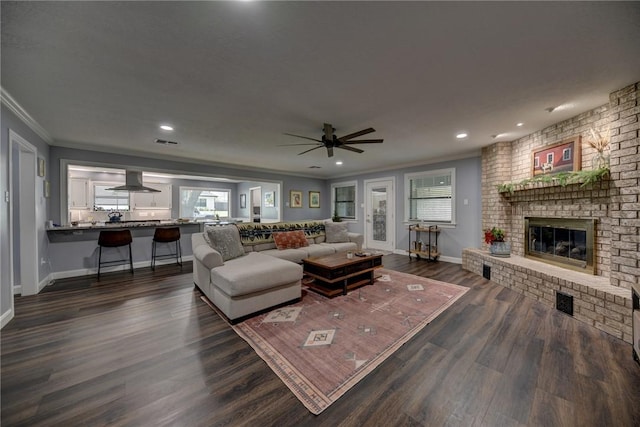 1600 Pecan St, Brenham, TX 77833 - living room with crown molding, baseboards, dark wood finished floors, a ceiling fan, and a brick fireplace