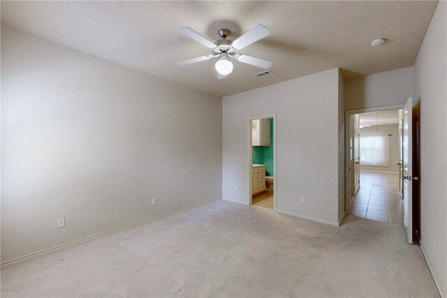 unfurnished bedroom featuring light colored carpet, attic access, baseboards, ensuite bathroom, and visible vents