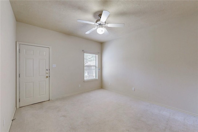 carpeted empty room featuring baseboards, a ceiling fan, and a textured ceiling