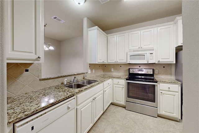 kitchen featuring visible vents, white appliances, light stone counters, a sink, and backsplash