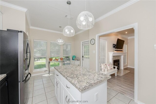 kitchen with pendant lighting, light hardwood / wood-style flooring, stainless steel fridge, a kitchen island, and white cabinetry