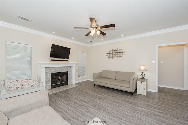 living room featuring hardwood / wood-style floors, ceiling fan, and crown molding