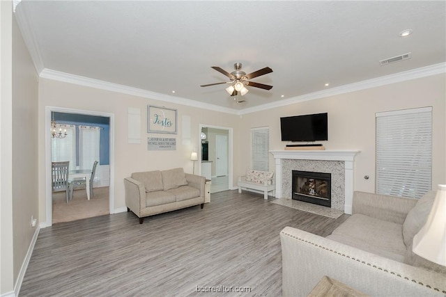 living room featuring ceiling fan with notable chandelier, light hardwood / wood-style flooring, and crown molding