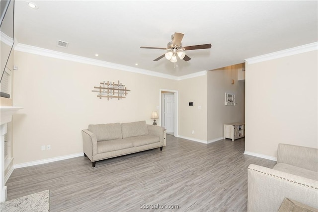 living room featuring a fireplace, wood-type flooring, ceiling fan, and crown molding