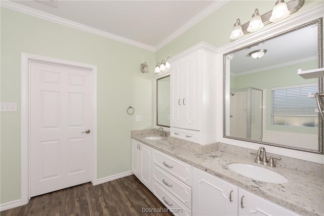 bathroom featuring wood-type flooring, vanity, a shower with door, and crown molding