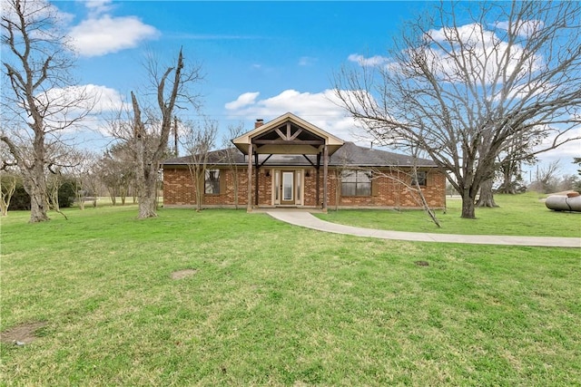 ranch-style house featuring a front yard, a chimney, and brick siding