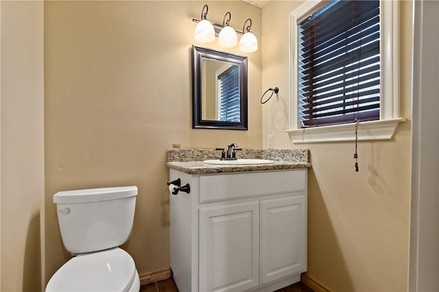 half bath featuring baseboards, vanity, and toilet