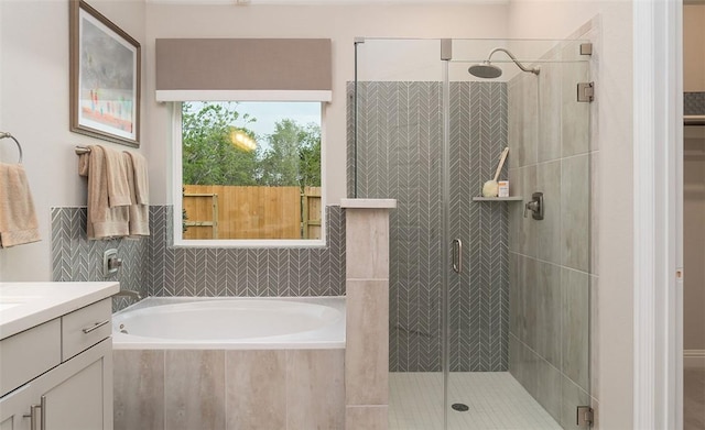 bathroom featuring a stall shower, vanity, and a bath