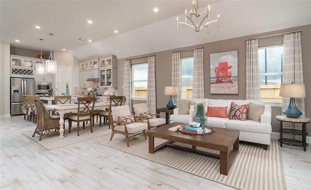 living room featuring light wood finished floors, baseboards, lofted ceiling, an inviting chandelier, and recessed lighting