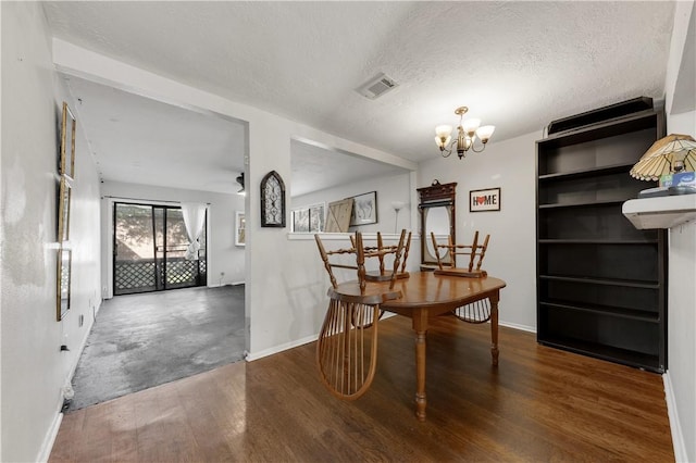 dining area with dark hardwood / wood-style floors, a textured ceiling, and a notable chandelier