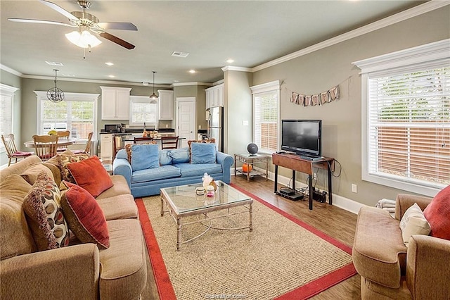 living room with light wood finished floors, baseboards, visible vents, crown molding, and recessed lighting