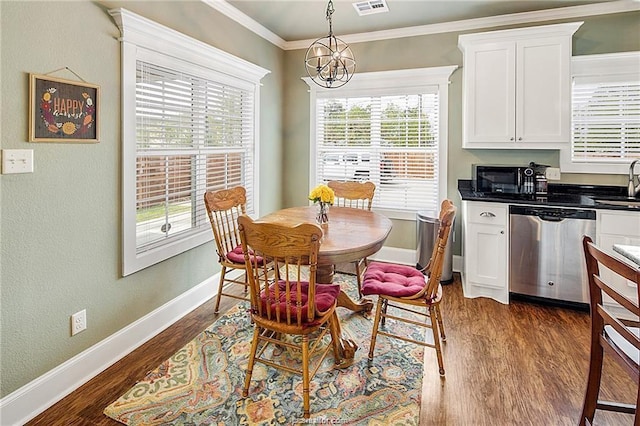 dining room with dark wood-style floors, ornamental molding, baseboards, and a notable chandelier