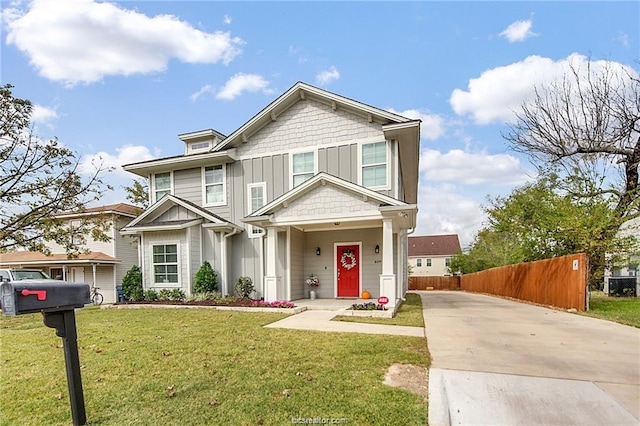 view of front of property with board and batten siding, a front yard, and fence