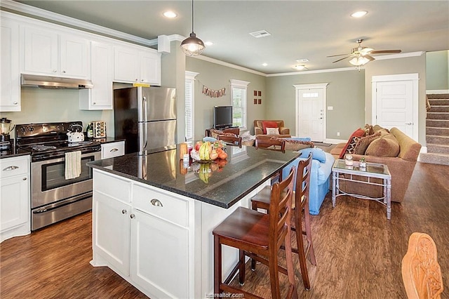 kitchen with under cabinet range hood, stainless steel appliances, a kitchen island, white cabinetry, and open floor plan