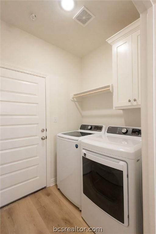 laundry room featuring cabinets, light hardwood / wood-style flooring, and washing machine and clothes dryer