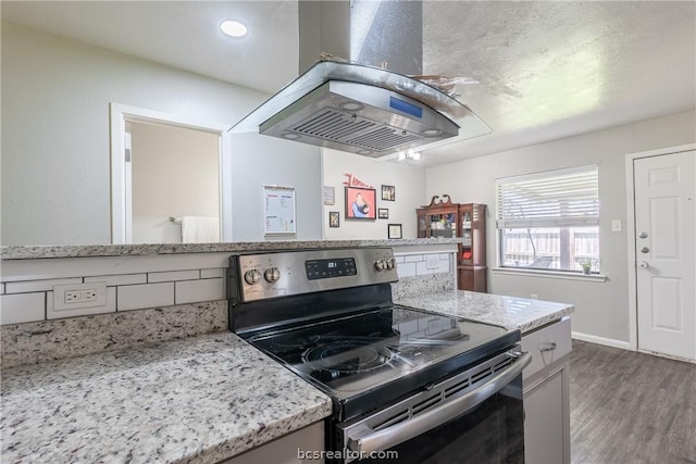 kitchen featuring island exhaust hood, electric range, light stone countertops, and hardwood / wood-style flooring