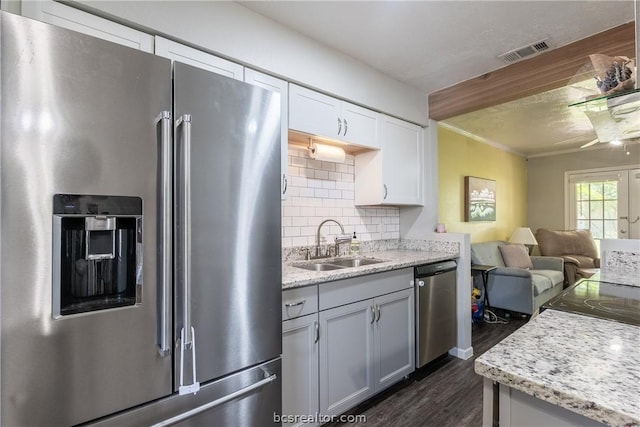 kitchen featuring dark wood-type flooring, sink, decorative backsplash, light stone counters, and stainless steel appliances