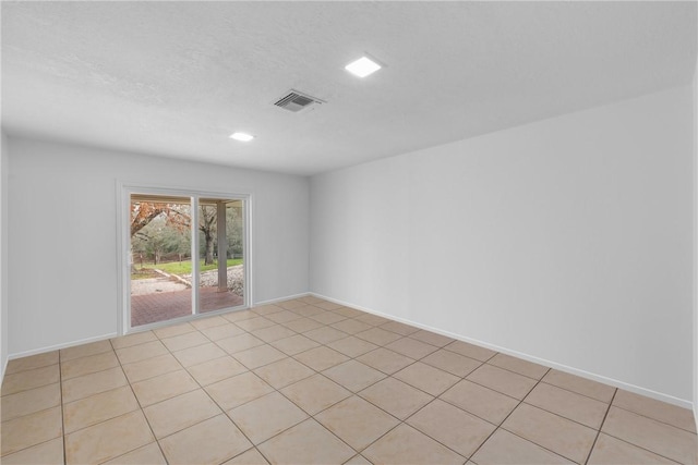 empty room with visible vents, a textured ceiling, and baseboards