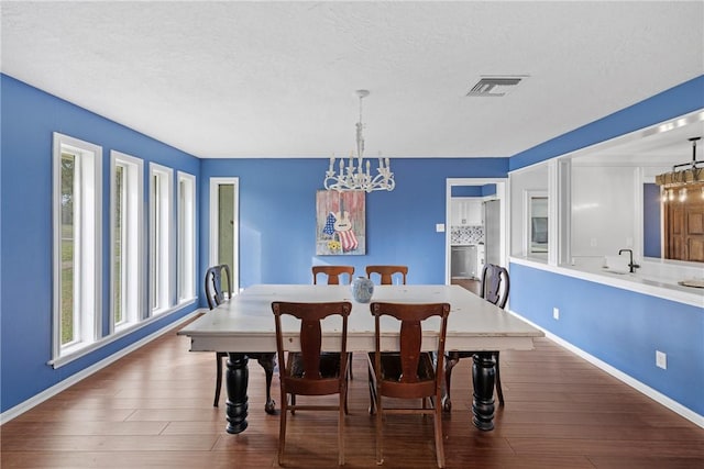 dining space featuring an inviting chandelier, wood finished floors, visible vents, and a wealth of natural light